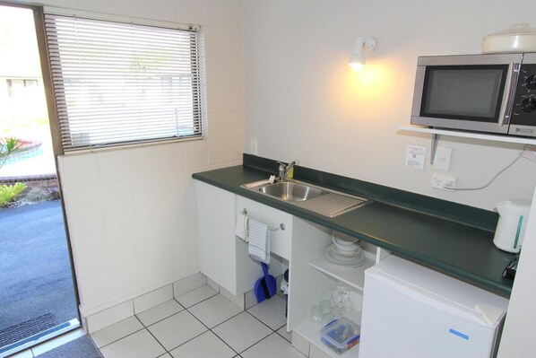 A compact kitchen with a sink, a microwave, and a small refrigerator.