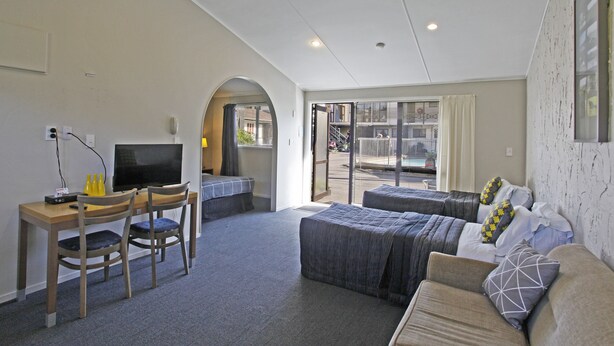Habitación de hotel con escritorio, dos sillas, cama y televisión.
