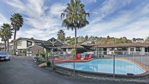 Zona residencial con piscina, palmeras y casas al fondo.