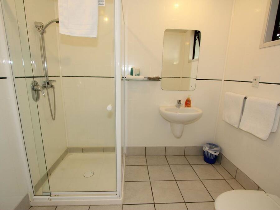 A bathroom with a glass-enclosed shower, a sink, a mirror, and a toilet.