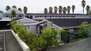 Un edificio residencial con techo plano, varios balcones y una fila de palmeras al fondo.