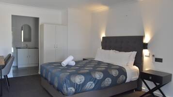 A hotel room with a bed, a desk, and a kitchenette.