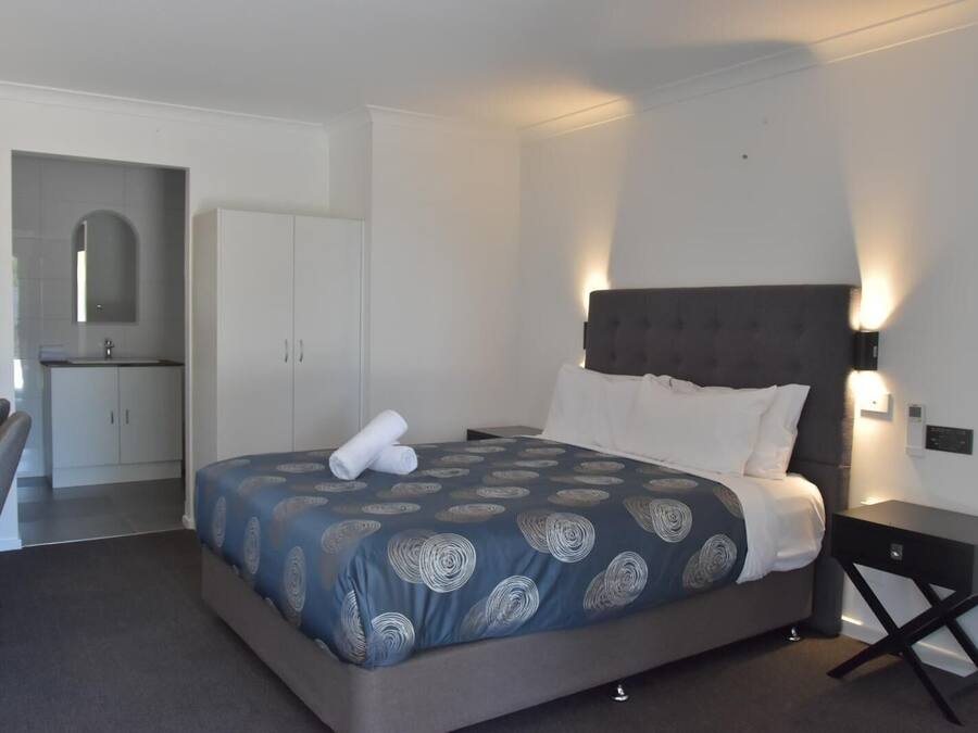 A hotel room with a bed, a desk, and a kitchenette.