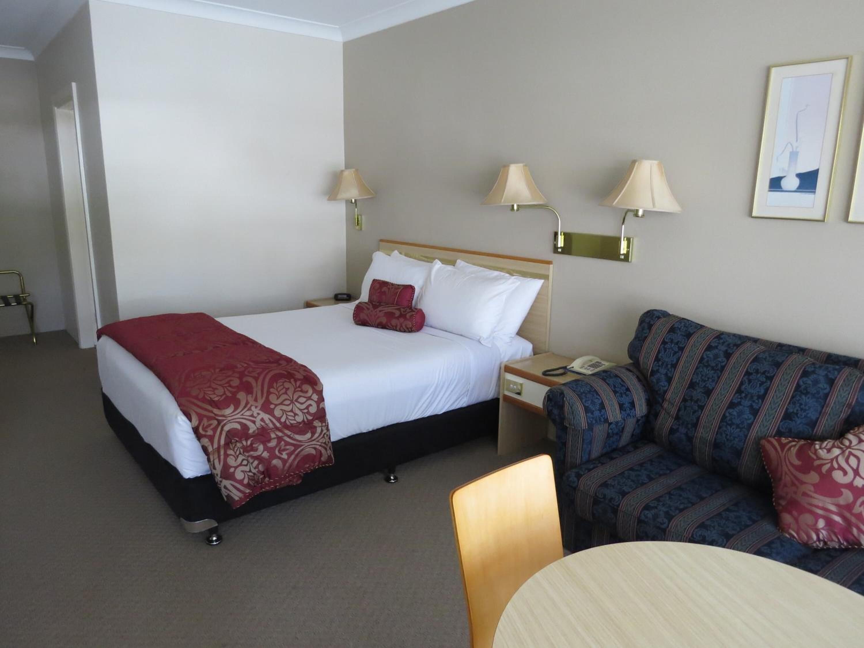 Una habitación de hotel con cama, sofá, mesa y dos lámparas de noche.