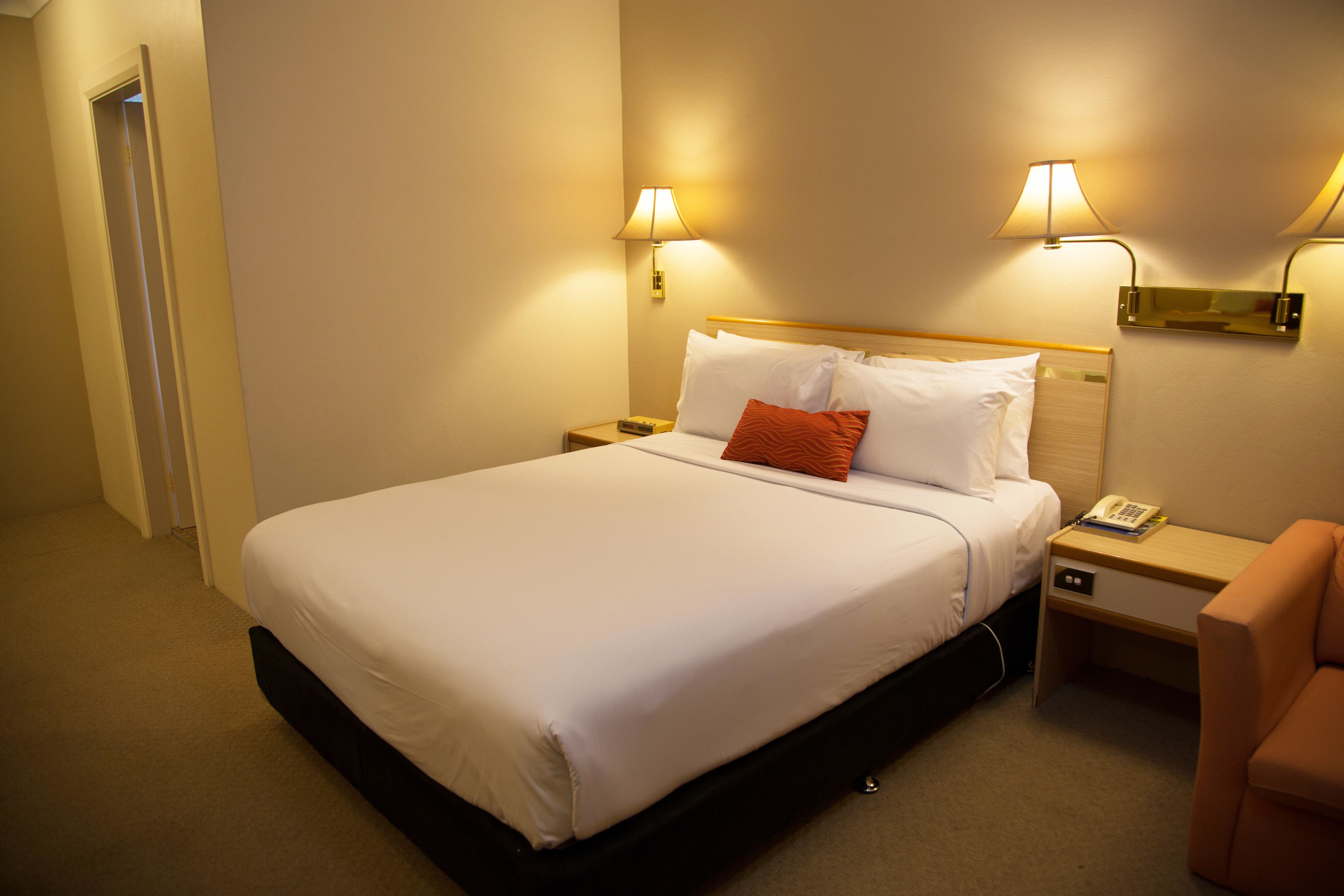 Une chambre d’hôtel avec un grand lit, deux lampes de chevet, une table de chevet, une chaise et une porte.