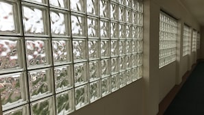 Un couloir doté d’une série de fenêtres dont les vitres, disposées selon un motif quadrillé, sont réfléchissantes.