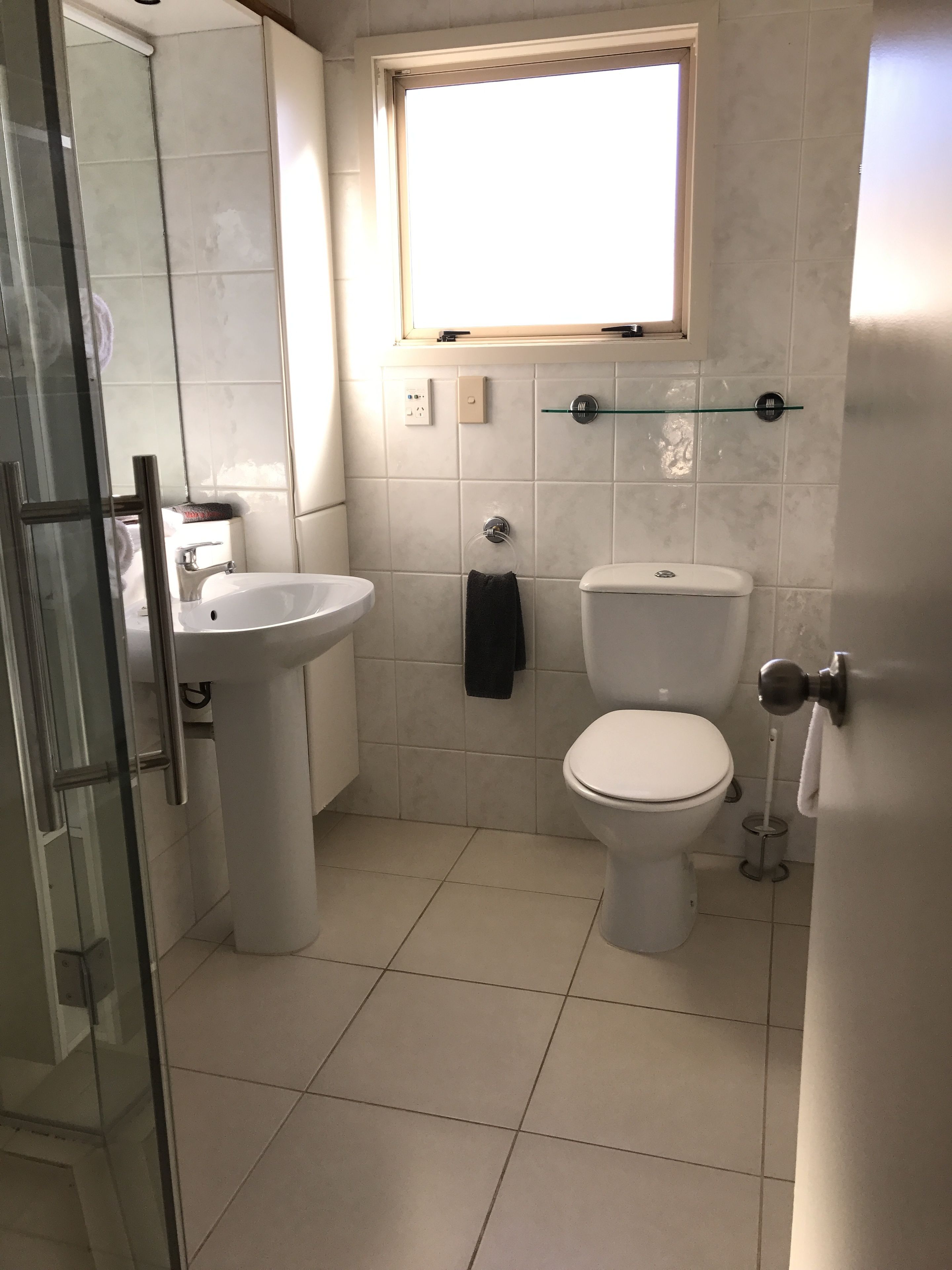 A bathroom with a toilet, sink, and glass shower enclosure.