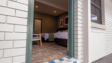 L’entrée d’un hôtel, avec un paillasson à carreaux, un lit et une chambre visible à l’intérieur.