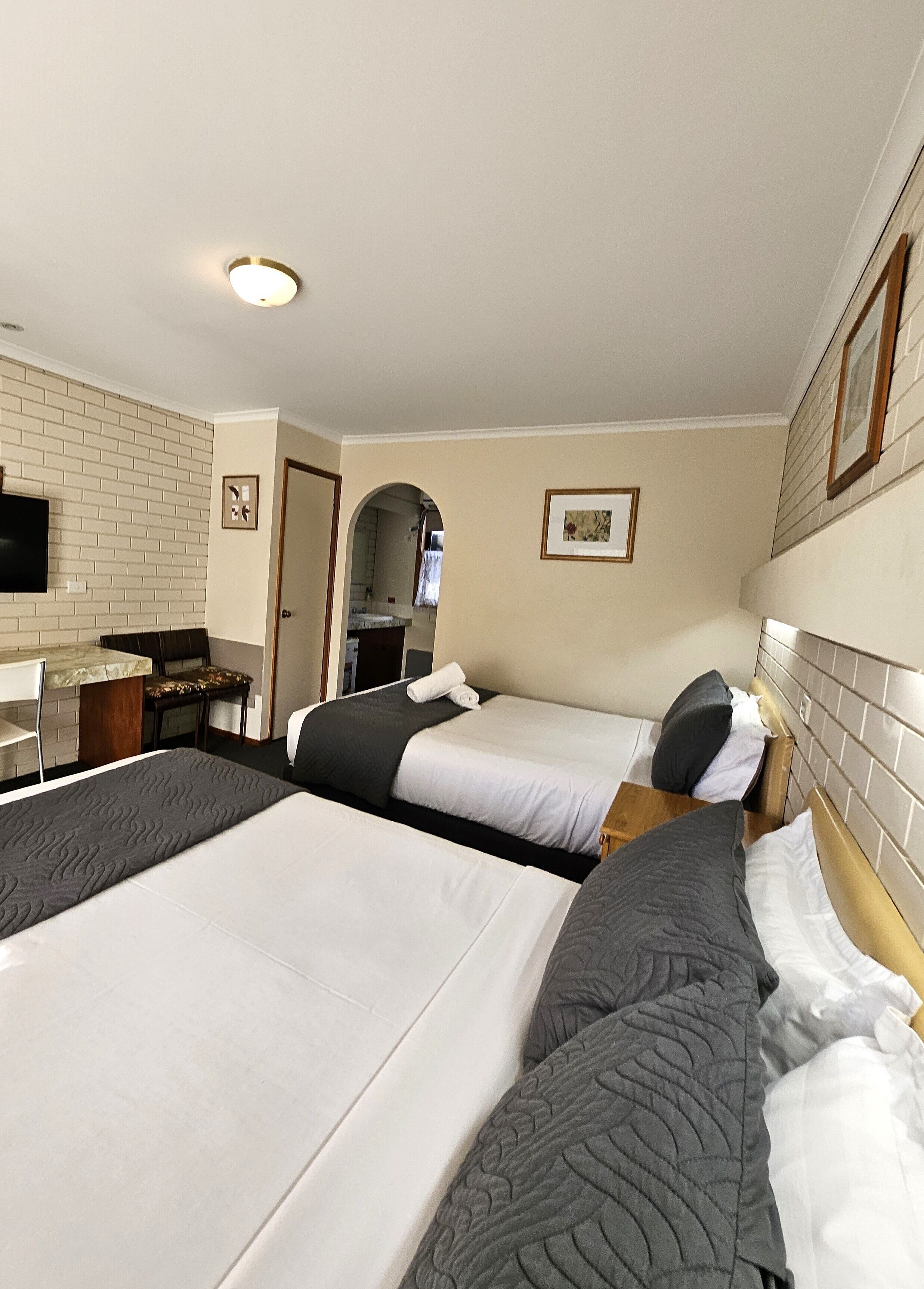 A hotel room with two beds, a desk, and a television.