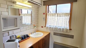 Una piccola cucina compatta con forno a microonde, tostapane, lavello e un piccolo frigorifero.