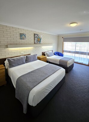 A hotel room with two beds, a brick-patterned wall, and artwork.
