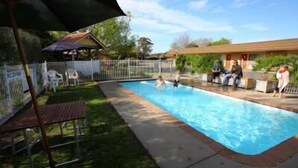 Una piscina con un'area recintata, una zona relax al coperto e un edificio sullo sfondo.