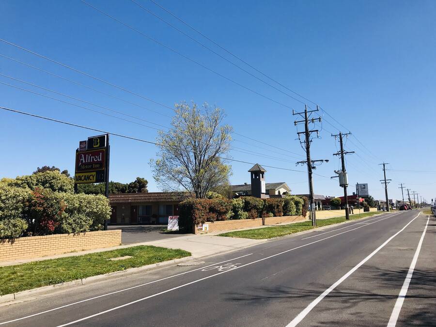 Vista de la calle con un letrero de motel, cielo despejado y una carretera con un carril bici.