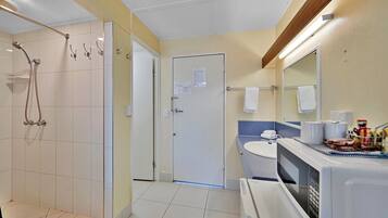 A bathroom with a shower, toilet, sink, and a mirror.