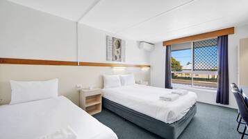 Une chambre d’hôtel avec deux lits, un bureau et une fenêtre donnant sur un paysage agréable.