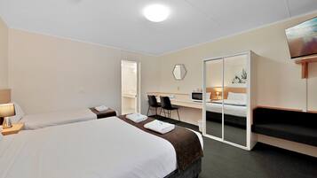 A hotel room with two beds, a desk with a chair, a TV, and a sliding door closet.