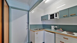 A compact kitchen with a sink, microwave, and a small countertop. - Oscar Motel (Bundaberg West)