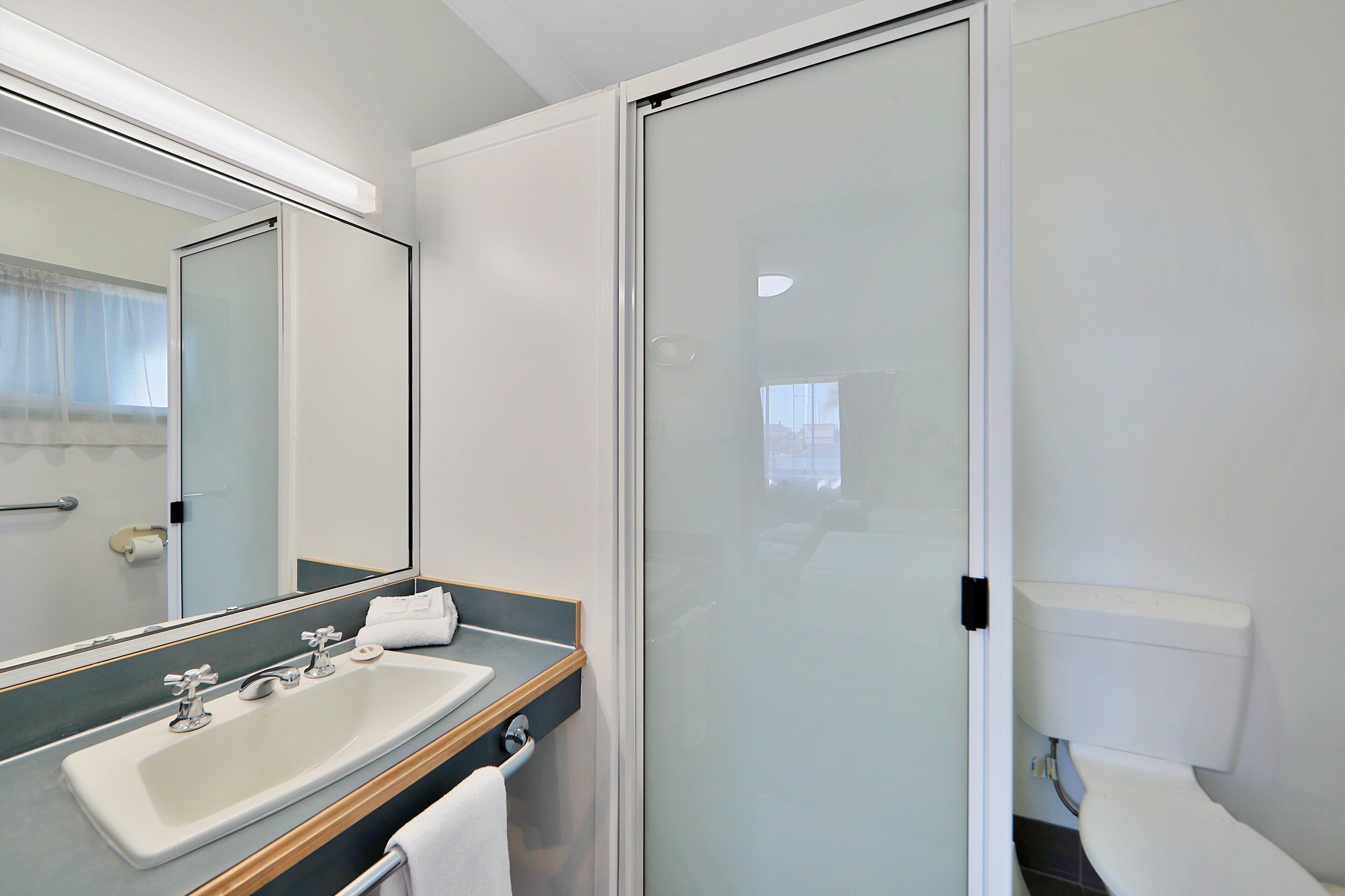 Ein modernes Badezimmer mit großem Spiegel, Waschbecken und Toilette.