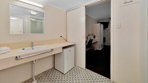 A bathroom with a sink, mirror, and a small refrigerator. - Oscar Motel (Bundaberg West)