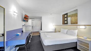 Habitación de hotel con cama, escritorio y silla. Hay un cuadro en la pared y un televisor sobre el escritorio.