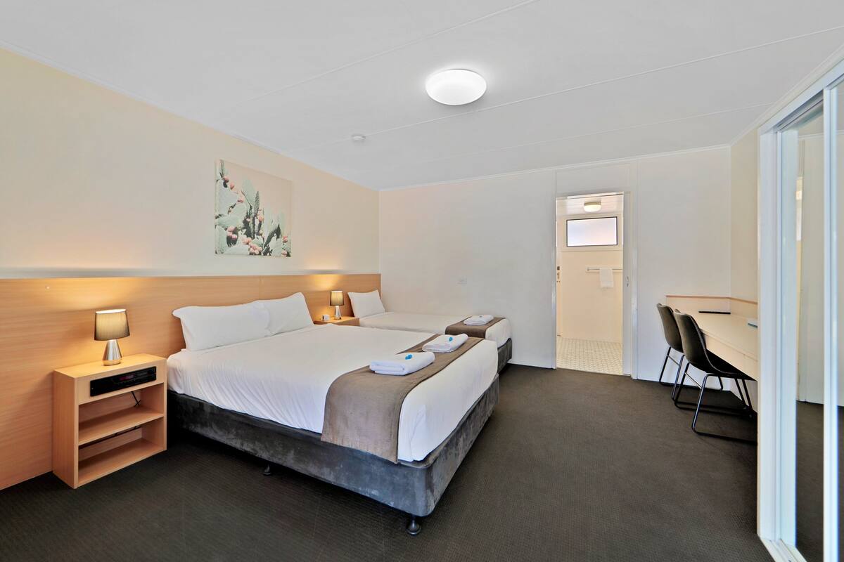 A hotel room with a large bed, bedside tables, a desk, and a chair.