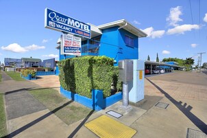 An Oscar Motel with a blue exterior, a signboard advertising vacancies, and a small parking area.