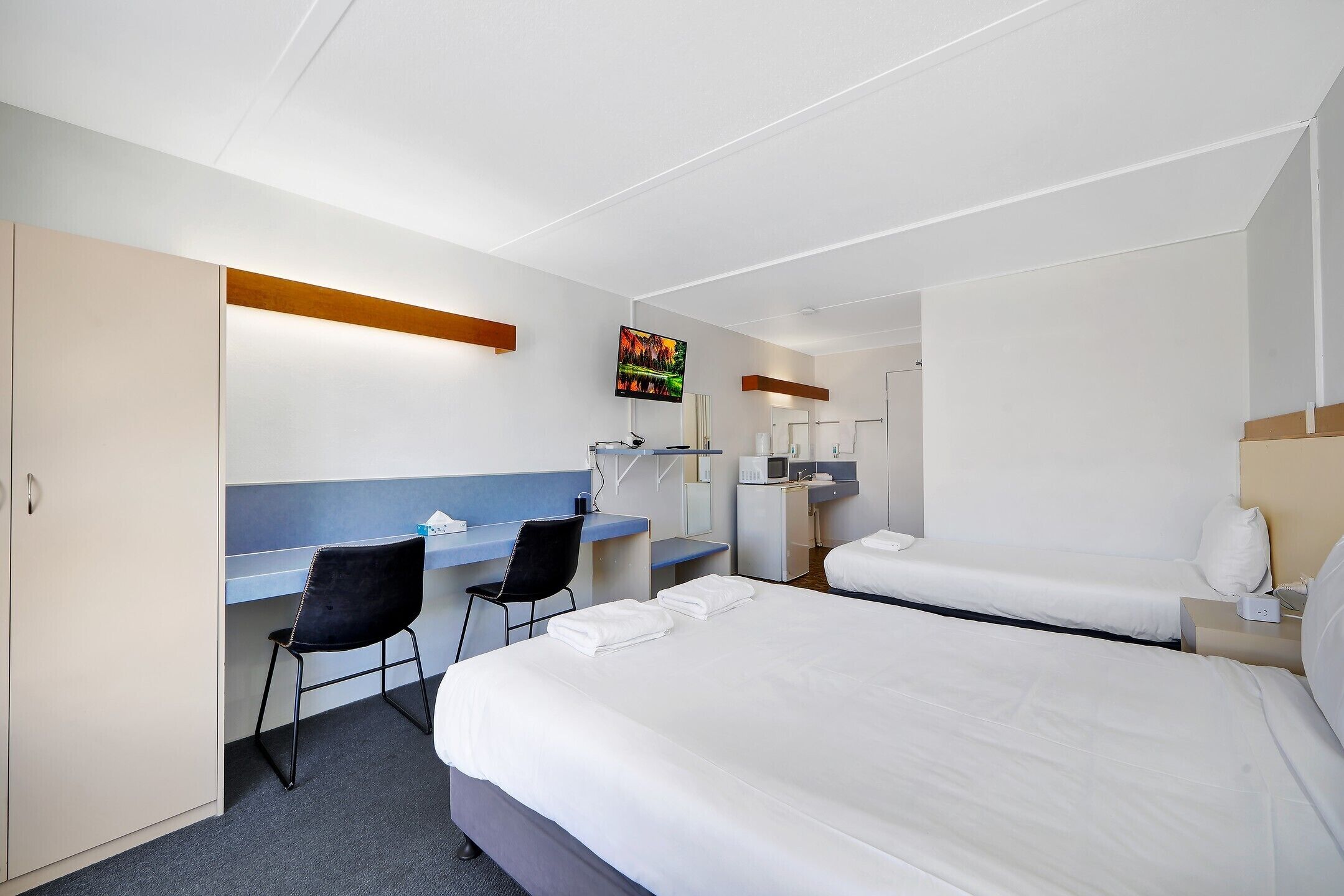 Une chambre d’hôtel équipée d’un lit, d’un bureau, d’une chaise, d’une télévision et d’une armoire.