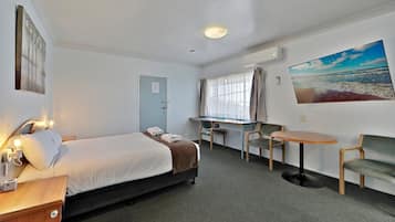 Een hotelkamer met een bed, een bureau, een stoel en een klein tafeltje.