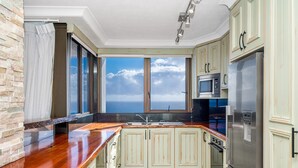 A kitchen with a view of the ocean, a stainless steel refrigerator, and a microwave. - Carool Apartments (Coolangatta)