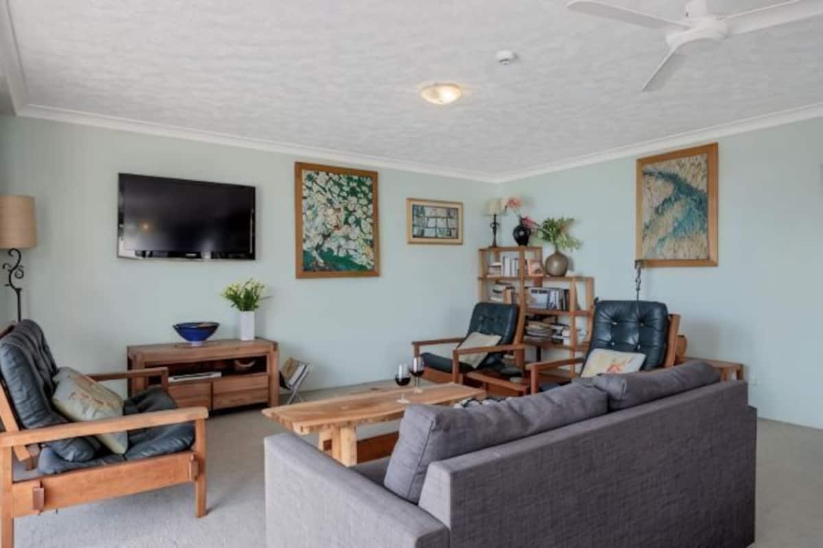 A living room with a sofa, chairs, a coffee table, a TV, and artwork on the walls.