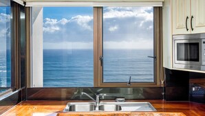 A kitchen with a large window offering a view of the ocean. - Carool Apartments (Coolangatta)