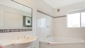 Un baño moderno con un lavamanos grande, una bañera y un espejo.