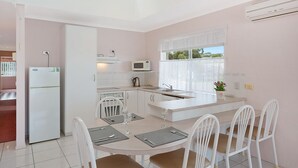 Una cocina moderna con electrodomésticos blancos, un comedor con mesa y sillas, y un ventanal con vistas.