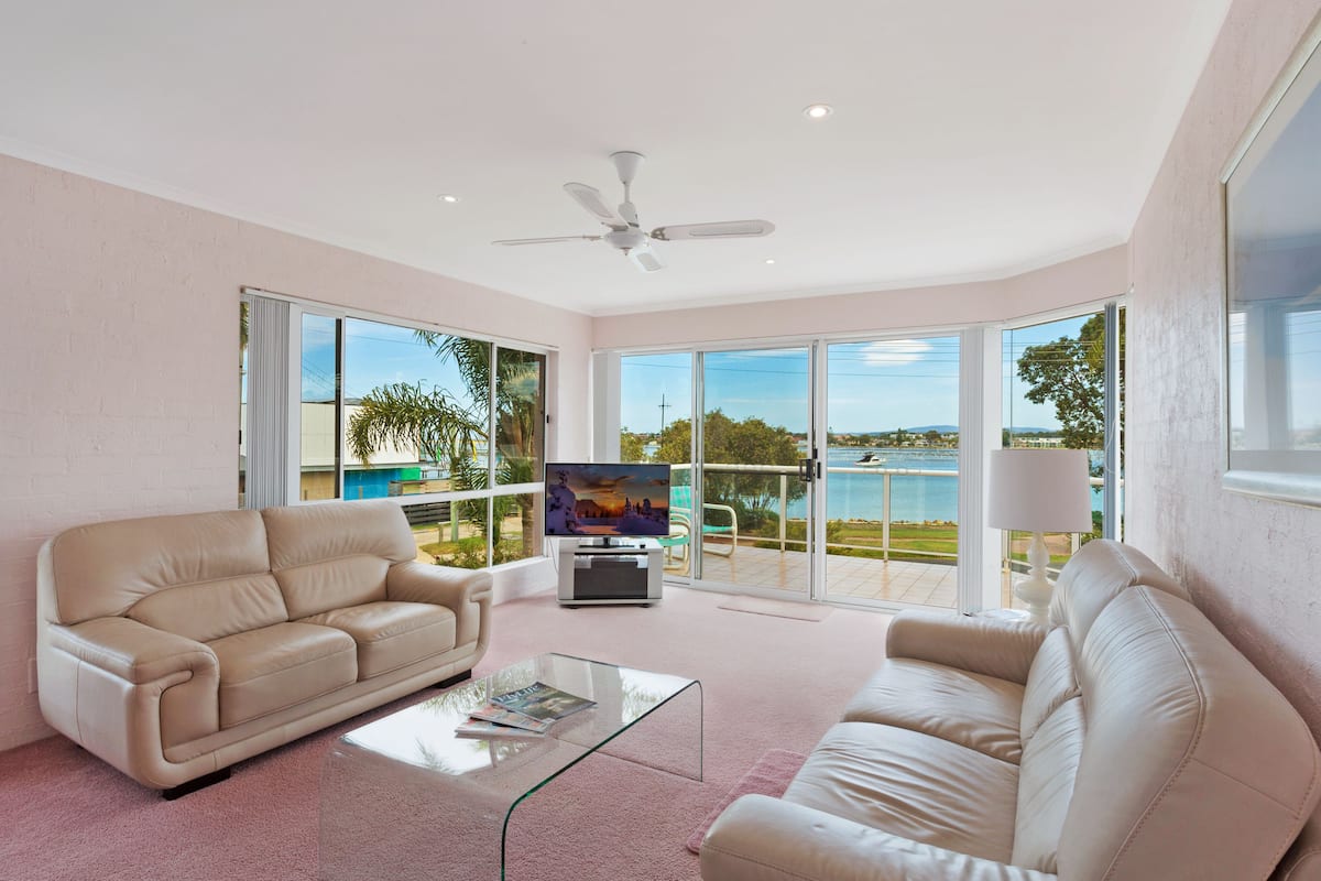 A spacious living room with a large TV, two sofas, and a glass coffee table.