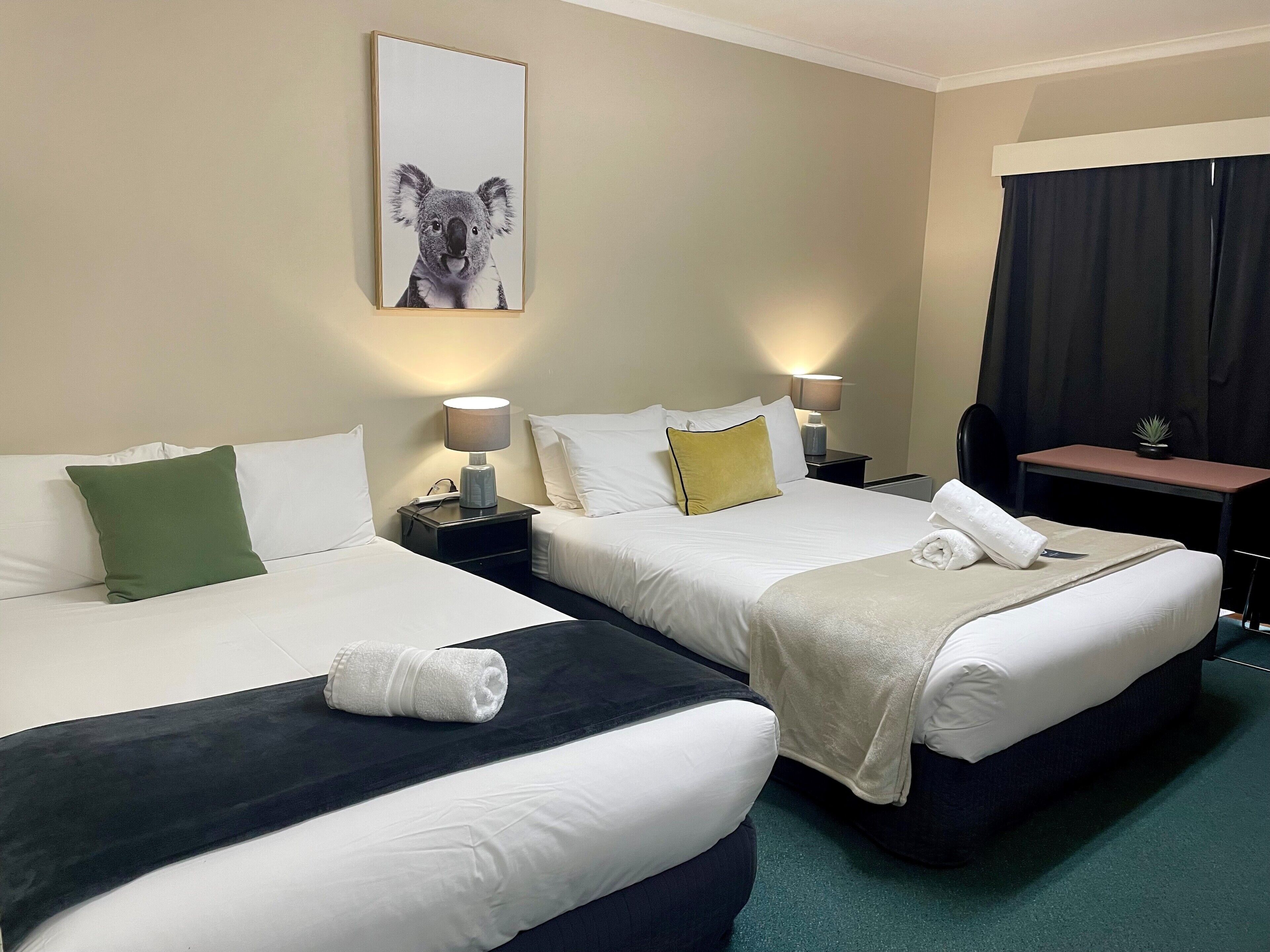 Ein Hotelzimmer mit zwei Betten, einem Schreibtisch und einem kleinen Tisch.