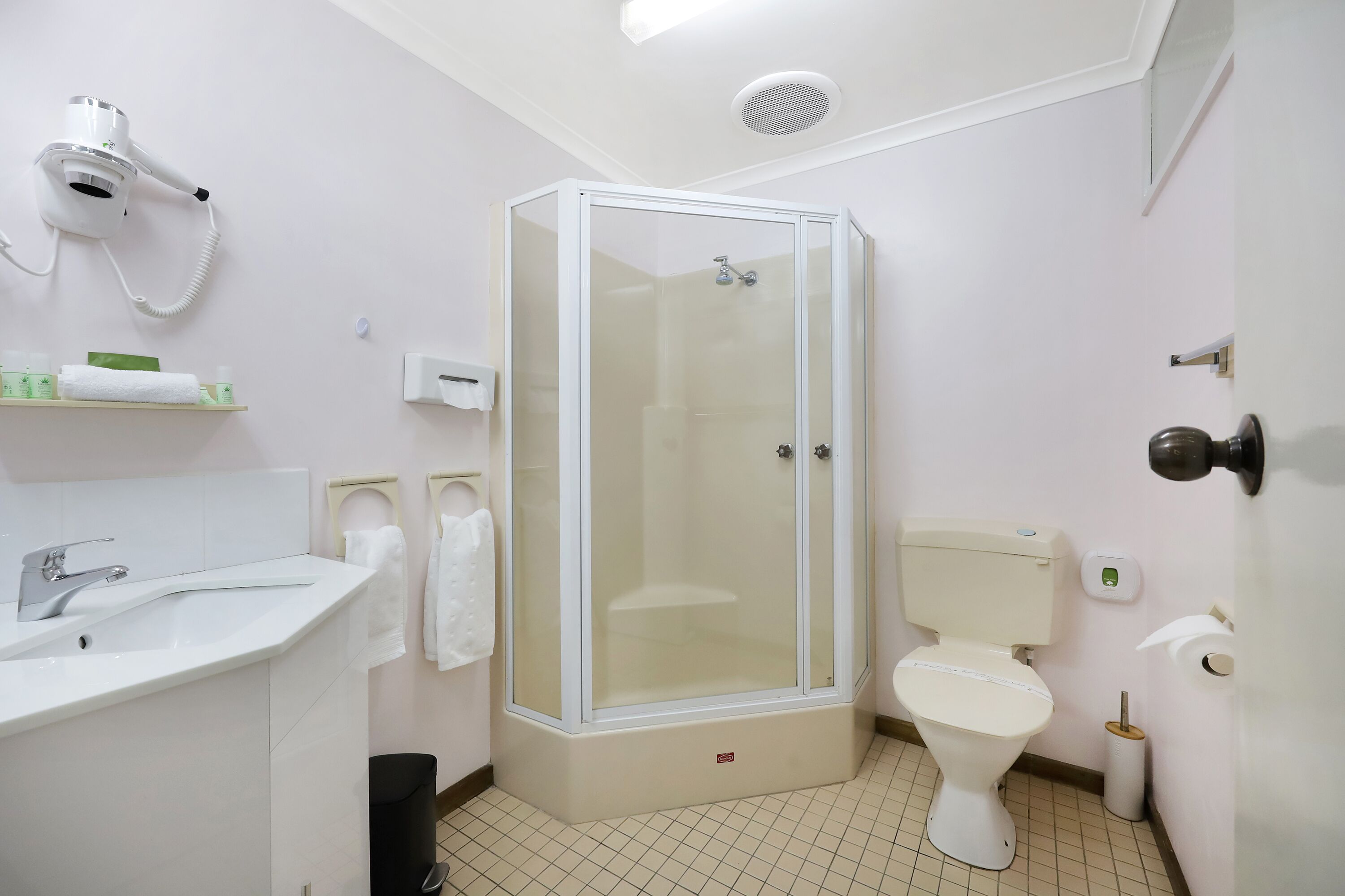 Un baño moderno con ducha de vidrio, un lavabo blanco y un inodoro.