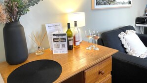 A hotel room with a wooden desk, a vase with dried plants, a wine bottle, and glasses. - City Heart Motel (Warrnambool)