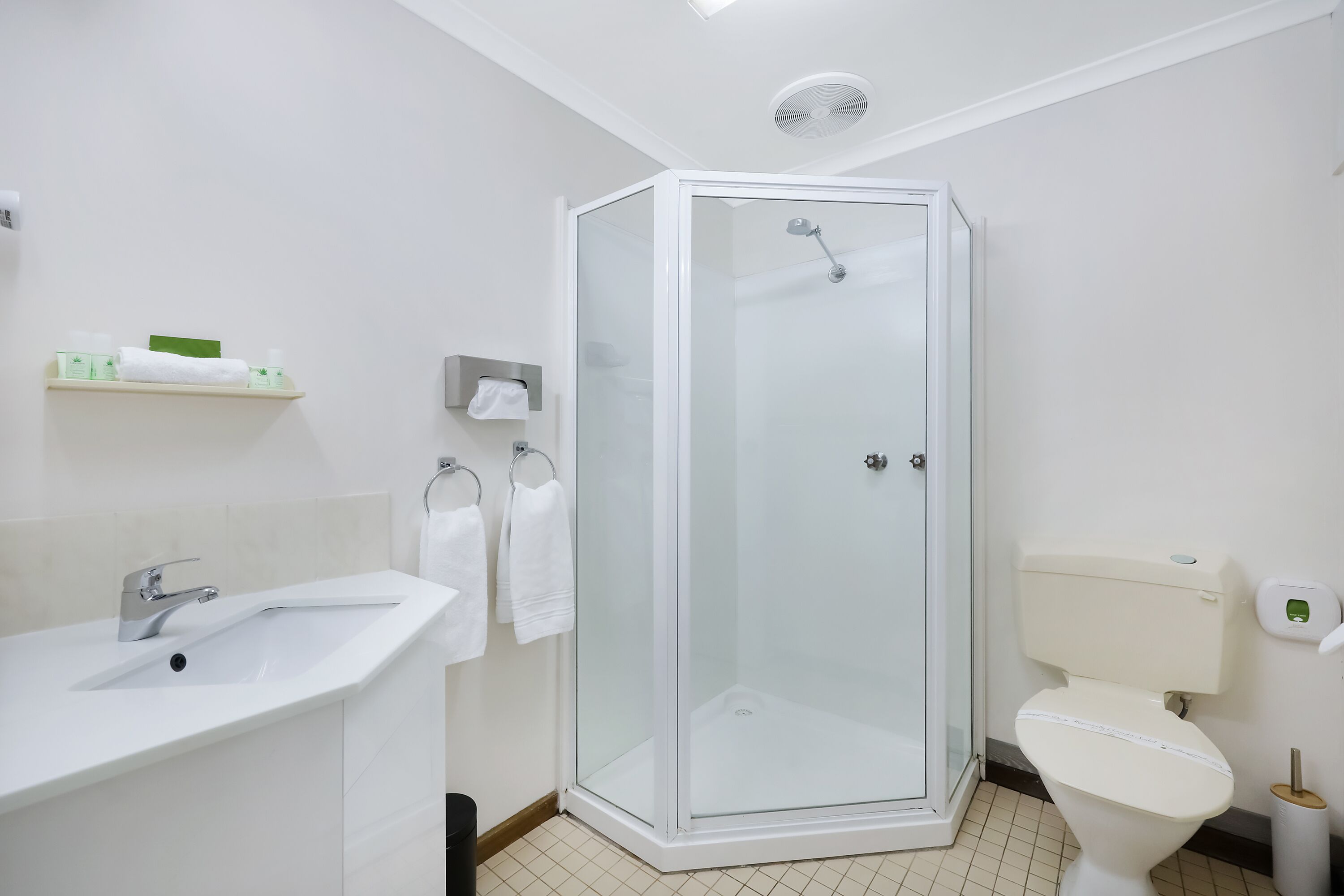 Et moderne badeværelse med en brusekabine i glas, en hvid vask og et toilet.