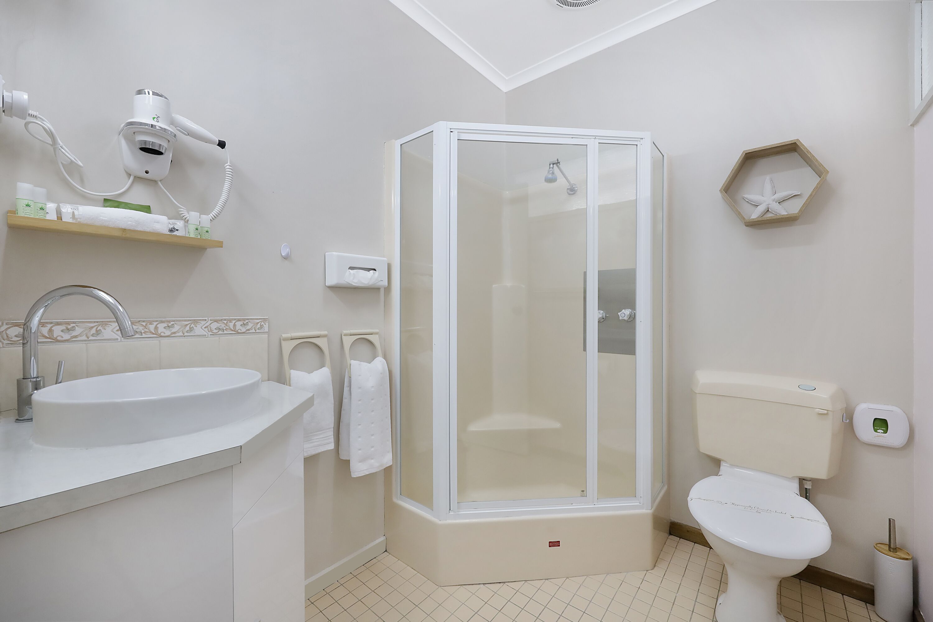Een moderne badkamer met een wastafel, toilet en een douchecabine met glazen wanden.