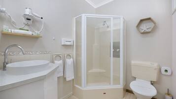 Een moderne badkamer met een wastafel, toilet en een douchecabine met glazen wanden.