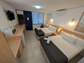 A compact hotel room with two beds, a kitchenette, a TV, and a window with blinds. - Moffat Beach Motel Caloundra (Moffat Beach)