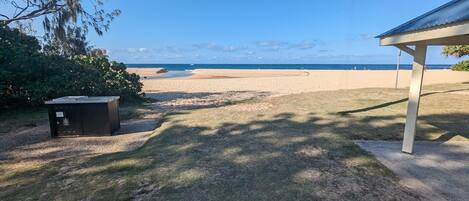 A beach view with a covered area and a small shed.