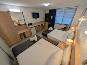 A hotel room with two beds, a desk, a microwave, and a TV. - Moffat Beach Motel Caloundra (Moffat Beach)