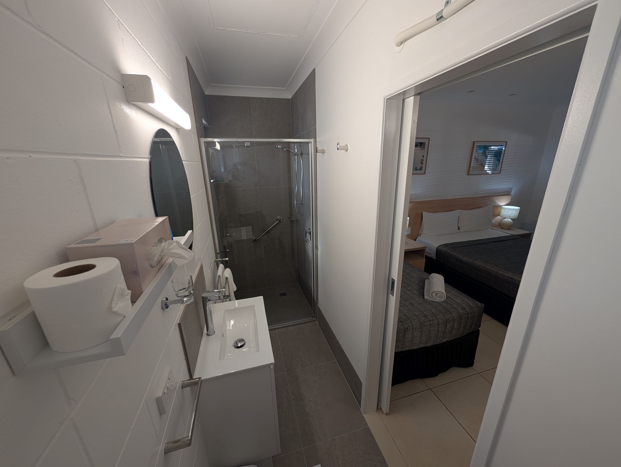 A compact hotel bathroom with a shower, toilet, and sink.
