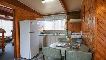 A compact kitchen with a refrigerator, stove, sink, and dining area with chairs and a table.