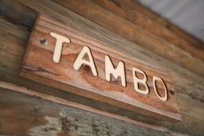 A wooden sign with the word "TAMBO" carved into it. - Lazy Acre Log Cabins (Lakes Entrance)