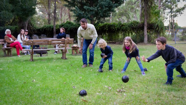 Un parque con mesas de picnic y gente jugando con una pelota.