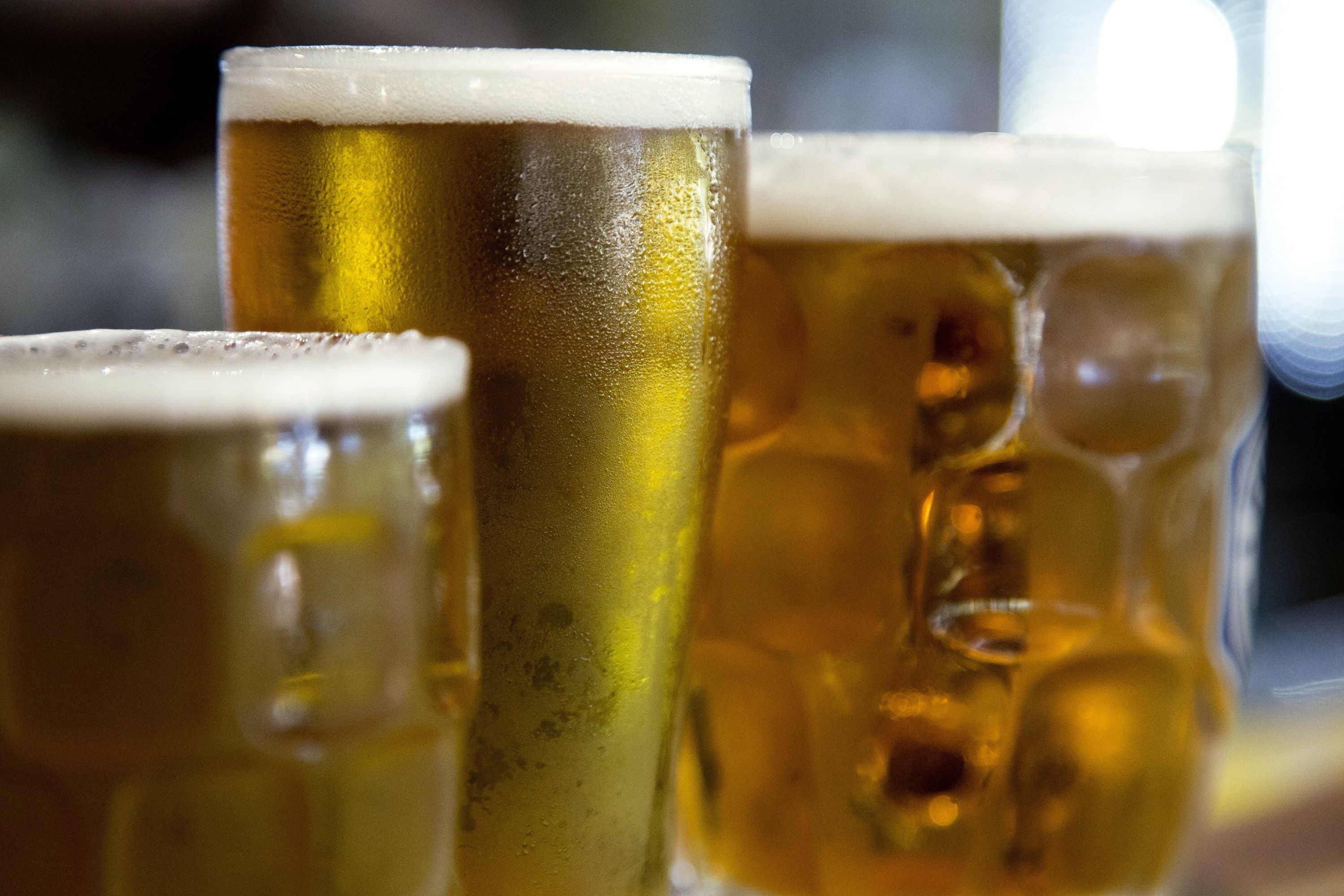 Drie bierglazen met schuim, vermoedelijk in een bar of café.