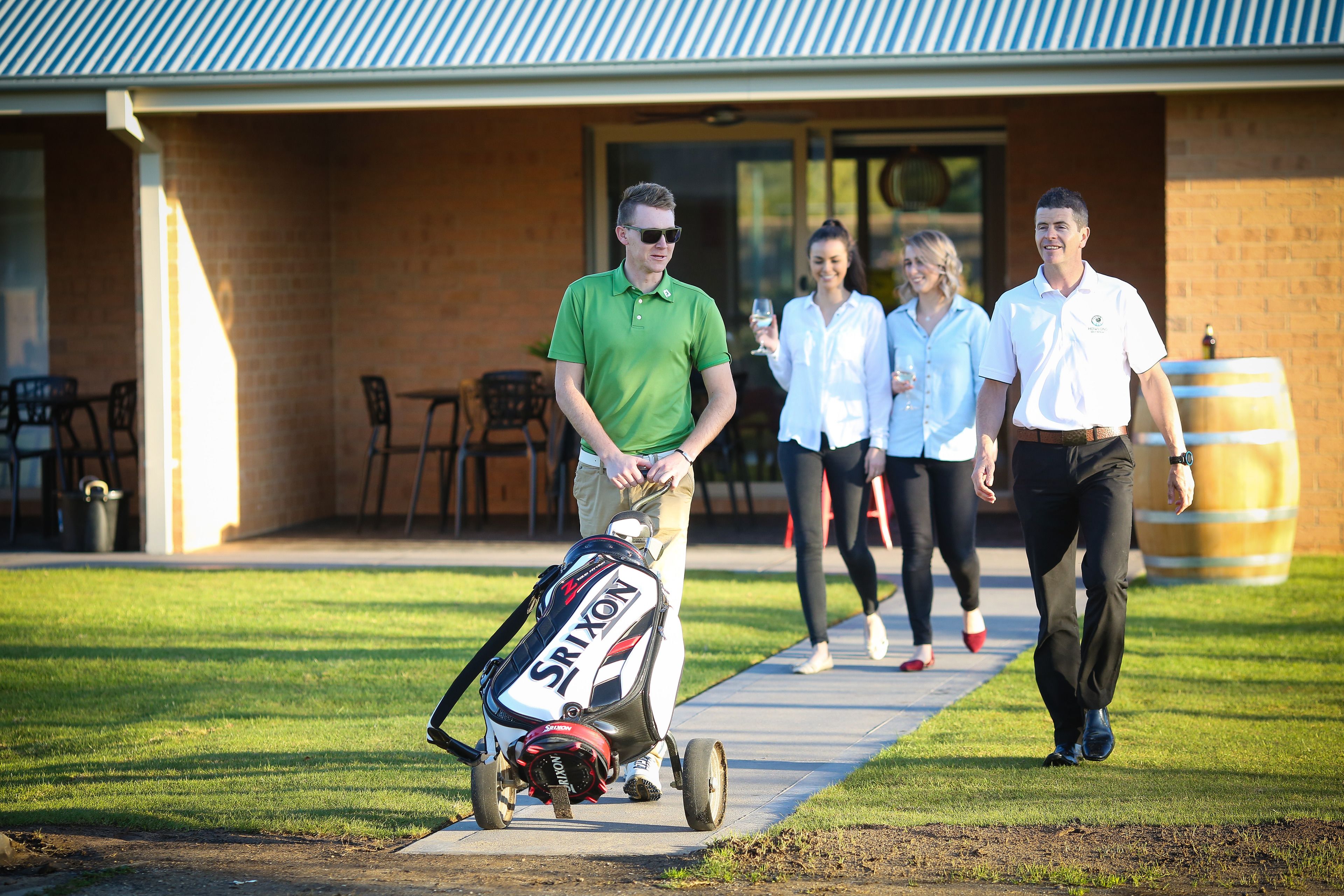 A golf cart with a Srixon bag, a brick building, and a grassy area.