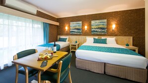 A hotel room with two beds, a dining table, and a small kitchen area.